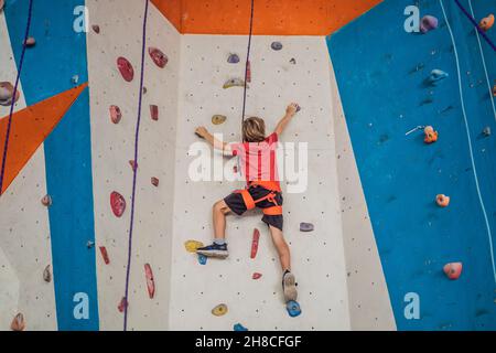 Boy at the climbing wall without a helmet, danger at the climbing wall Stock Photo