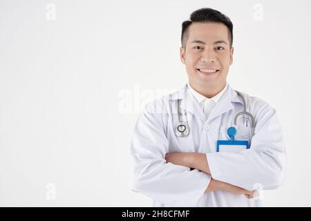 Portrait of smiling young general practitioner in white labcoat folding arms and looking at camera Stock Photo