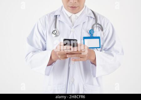 Serious general practitioner reading text messages on smartphone from patient or colleague Stock Photo