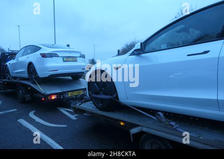 Tesla Electric car on transporter Northampton UK being delivered to a garage being transported on trailer trailers white car electric vehicles new Stock Photo