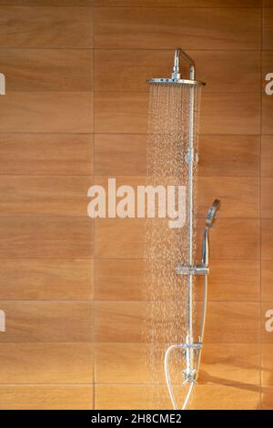 Outdoor shower head for the bath and showering cold water to body before jumping in the resort pool. Stock Photo