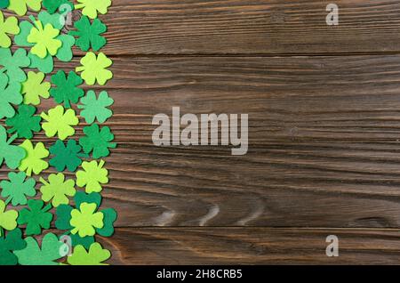 Happy Saint Patrick's mockup of handmade felt shamrock clover leaves on wooden background. Stock Photo