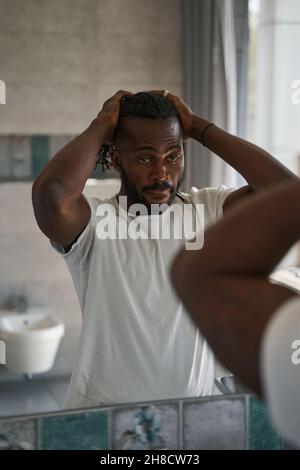 Serious focused African American guy standing in bathroom Stock Photo