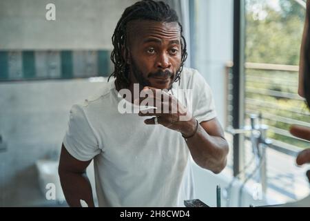 Focused guy examining skin on his face Stock Photo