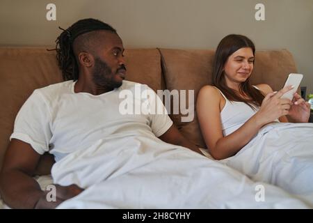 Sad guy looking at woman focused on her cellphone Stock Photo