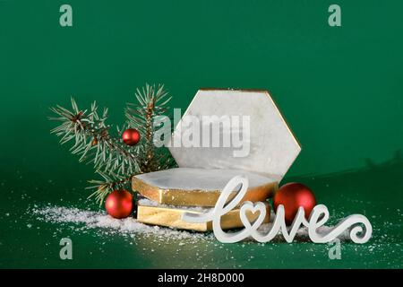 Marble hexagon podium with winter Christmas holiday decor. Red white baubles, berries on fir twigs, wooden word Love. Stock Photo