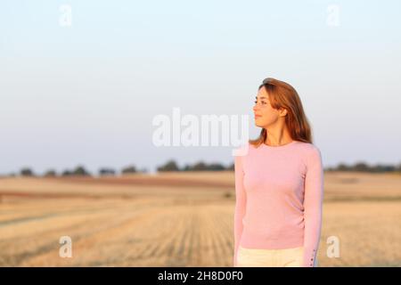 Woman contemplating views in a harvested field at sunset Stock Photo