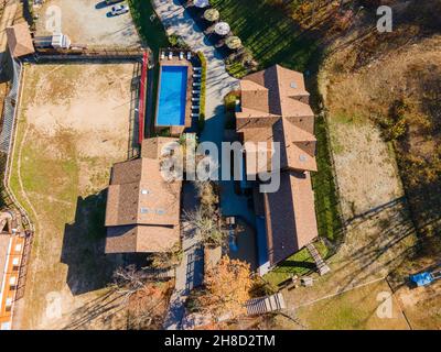 Country recreation center located in the woods with a large blue pool, sun loungers and tables. Photo from the drone. Stock Photo