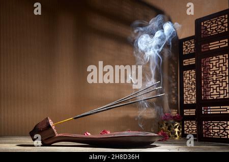 Smoke from burning incense sticks standing on lotus incense holder Stock Photo