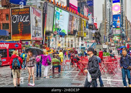 NEW YORK, USA - JUNE 10, 2013: People visit NY Times Square in the rain. Times Square has over 39 million annual visitors. It is an important landmark Stock Photo