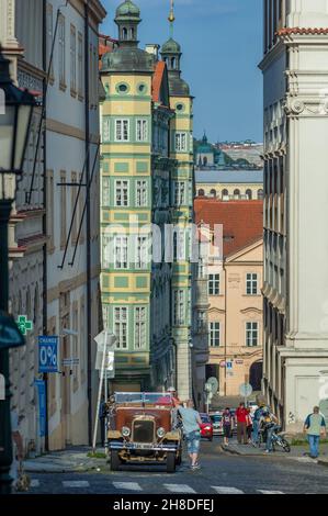 Green onion domes top the colourful Palace Smiřických in Malostranské náměstí, while a vintage Praga sightseeing tour car awaits custom in the street Stock Photo