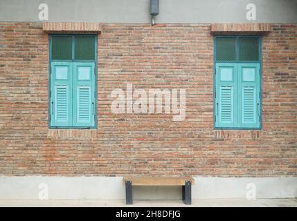 Brick building with blue wooden shuttered windows and benches Stock Photo