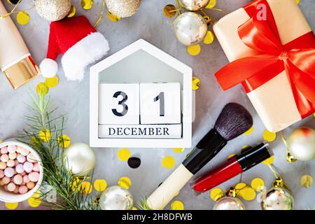 Christmas flat lay with makeup cosmetic products on gray concrete background with wooden calendar. Happy new year 2022 and merry xmas mockup Stock Photo