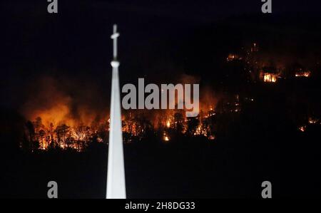 Pinnacle, North Carolina, USA. 29th Nov, 2021. Flames on Pilot Mountain rise from behind a steeple at the Friendly Chapel Church as a fire fueled by dry and windy conditions that started off a popular trail at the State Park on Saturday afternoon grew to encompass more than 250 acres, forcing campers to evacuate and the park to close for the foreseeable future. (Credit Image: © Bob Karp/ZUMA Press Wire) Stock Photo