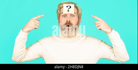 Beard man question mark in head, solution problems. Thinking man with question mark on blue background. Man with question mark on forehead looking up Stock Photo