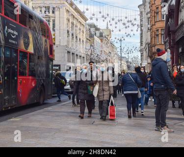 London, UK. 29th November 2021. People wearing face masks on Oxford Street. Coronavirus restrictions have been reintroduced in the UK, with mandatory face masks in shops and on public transport, to help stop the spread of the new Omicron variant. People who refuse to wear masks face a fine of £200. Stock Photo