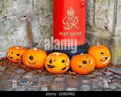 Group of five pumpkins laid out in front of a traditional British red pillar box at Halloween. Stock Photo
