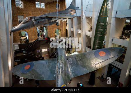 Imperial War Museum Lambeth London UK England November 2021 The main entrance atrium showing a Harrier ‘Jump’ Jet, a Spitfire that flew in the Battle Stock Photo