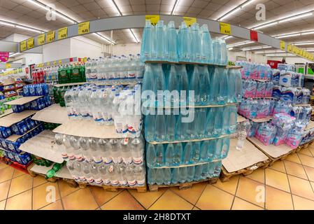 Fossano, Italy - November 29, 2021: Variety plastic bottles of mineral water stacked on pallets for sale in Italian discount supermarket Stock Photo