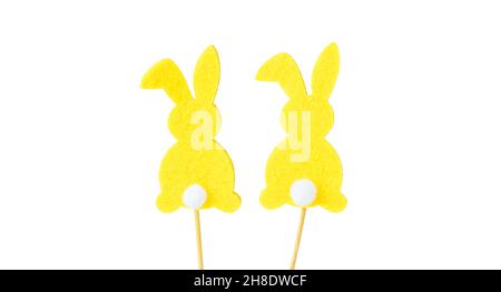 Yellow easter bunny rabbits with white tails, silhouette, on a wooden stick, isolated on a white background. Souvenir, decoration for Easter. Easter c Stock Photo