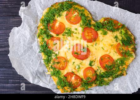 Valentines Day food. Heart shaped pizza with greens and mushrooms, vegetables on a dark background. Valentine's day concept. Top view. Copy space Stock Photo