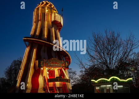 A great red and yellow Helter-Skelter spiral illuminated by hundreds of small bulbs just before sunset, Harrogate, North Yorkshire, England, UK. Stock Photo