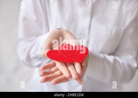 woman hands holding two hearts on open palm on background of white shirt. shallow depth of field photo Stock Photo
