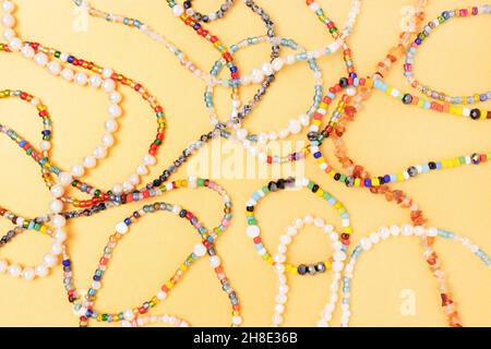 Necklaces and bracelets made from colorful beads and pearls on a golden background. Stock Photo