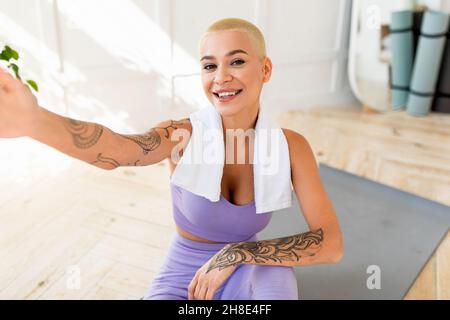 Positive young lady taking selfie during break from home workout, making photo of herself during domestic training Stock Photo