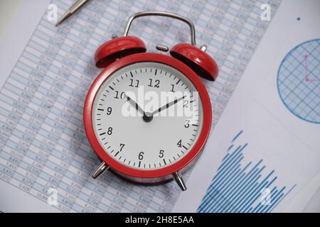 Red alarm clock lying on documents with graphs and numbers closeup Stock Photo