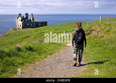 woman walking on coastal path to Dunskey Castle, Portpatrick, Rhins, Wigtownshire; Dumfries & Galloway; Scotland Stock Photo