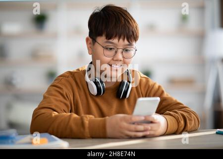 Chubby asian kid using mobile phone at home Stock Photo