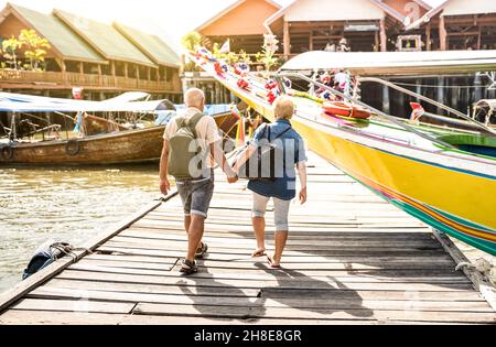 Happy senior couple walking holding hand at Koh Panyi muslim floating village - Active elderly and travel lifestyle concept with retired mature people Stock Photo