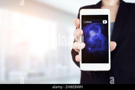 Hand hold white smartphone with digital hologram sign on light blurred background. Searching Internet Data. Web Browsing Concept. Searching informatio Stock Photo