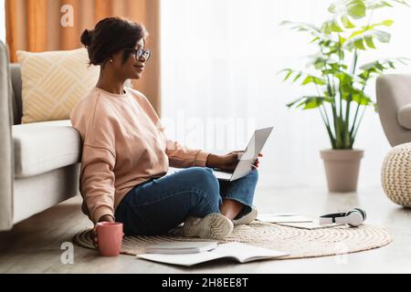 Black Lady Using Laptop Working And Having Coffee At Home Stock Photo