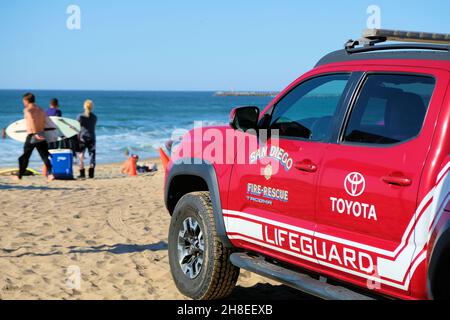 A red Toyota San Diego, California lifeguard fire and rescue truck on Ocean Beach with beachgoers in the background; sunny day in Southern California. Stock Photo