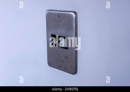 Angled view of a Down elevator button panel on a white wall inside a business building Stock Photo