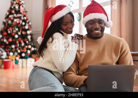 Portrait of happy black couple using laptop on Xmas eve Stock Photo