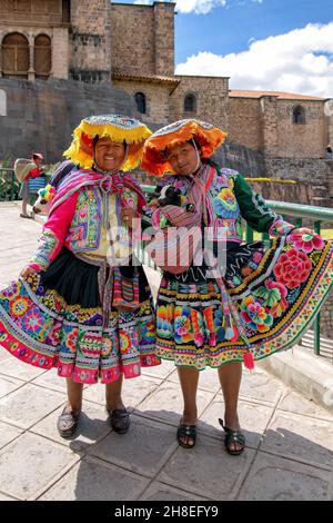 Quechua women wearing traditional clothing in front of the Qorikancha in Cusco Stock Photo