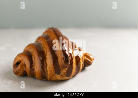 Freshly backed french croissant with chocolate filling lies on the table. Delicious French pastries. Copy space. Stock Photo