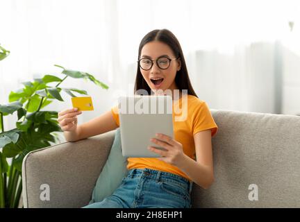 Online shopping concept. Surprised asian lady using digital tablet and credit card, buying and ordering things online Stock Photo