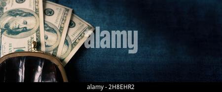 Black small vintage open wallet with roll of dollars on a blue jeans background. Copy space. Stock Photo