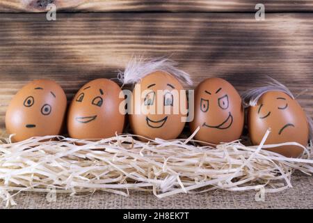 Five brown eggs with funny faces on wooden background Stock Photo