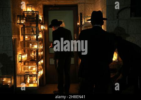 Jerusalem. 29th Nov, 2021. Ultra-Orthodox Jewish men pray in front of candles during Hanukkah in Jerusalem, on Nov. 29, 2021. Credit: Muammar Awad/Xinhua/Alamy Live News Stock Photo