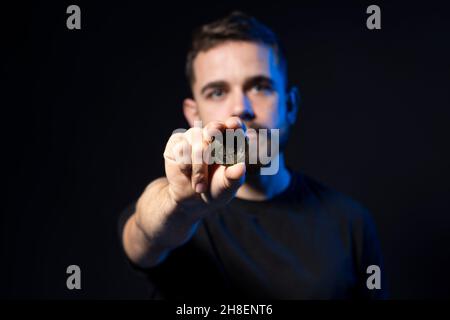 A young bearded man is holding excited a bitcoin looking at the camera. BTC the new virtual money. Stock Photo