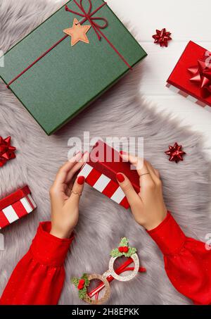 Womans hands with trendy red manicure holding gift box on fluffy carpet Stock Photo
