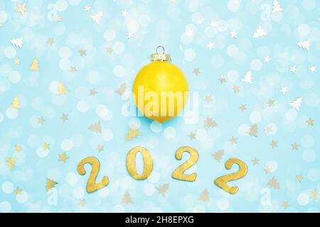 New Year 2022 greeting card with lemon and golden glitters on blue background. Top view