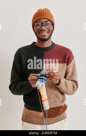 Minimal vertical portrait of young African-American man knitting and smiling at camera Stock Photo