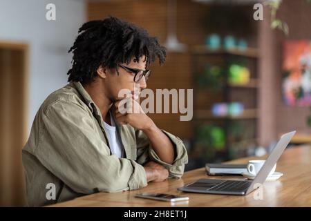 Young Black Male Entrepreneur Working With Laptop At Modern Coffeeshop Stock Photo