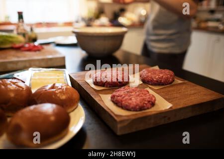 Close up fresh hamburger patties and buns on kitchen counter Stock Photo